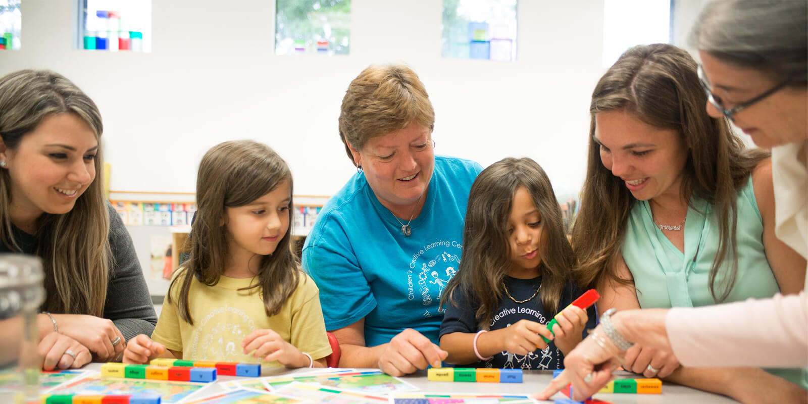 A group of children engaging with educational materials and two teachers. 